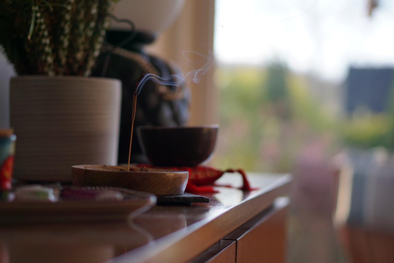 Eine dunkle Schale, Pflanzen und kleine persönliche Dinge im weichen Licht am Fenster.